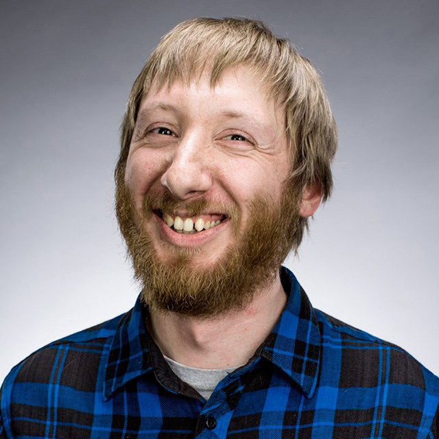 Фото Михаила Когана, сооснователя проекта - мужчина с рыжей бородой в синей клетчатой рубашке улыбается